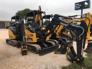 John Deere and JCB mini excavators with buckets and dozer blades on the 4-T Rental & Sales yard in Buchanan Dam, TX
